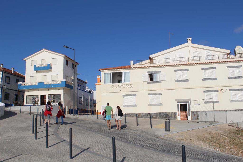a group of people walking down a street in front of a building at Apartamento Sto Estevão in Zambujeira do Mar