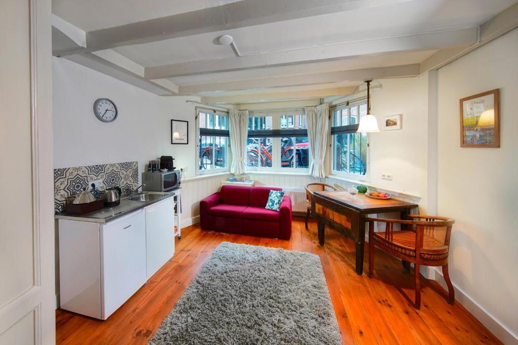 a kitchen and a living room with a red couch at 16 sous in Utrecht