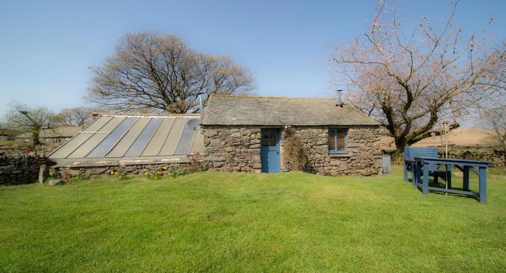 an old stone house with a table in front of it at Woodend Schoolhouse in Broughton in Furness