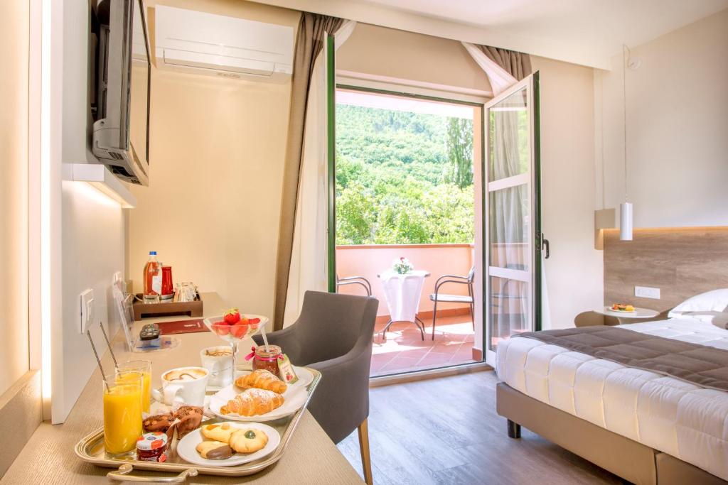 una camera con un letto e un tavolo con un vassoio di cibo di Guesia Village Hotel e Spa a Foligno