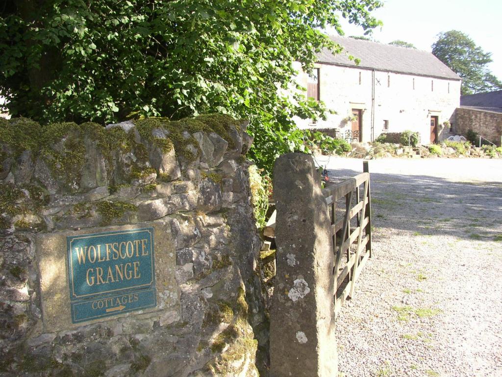 a sign on a stone wall in front of a house at SWALLOWS RETURN in Hartington