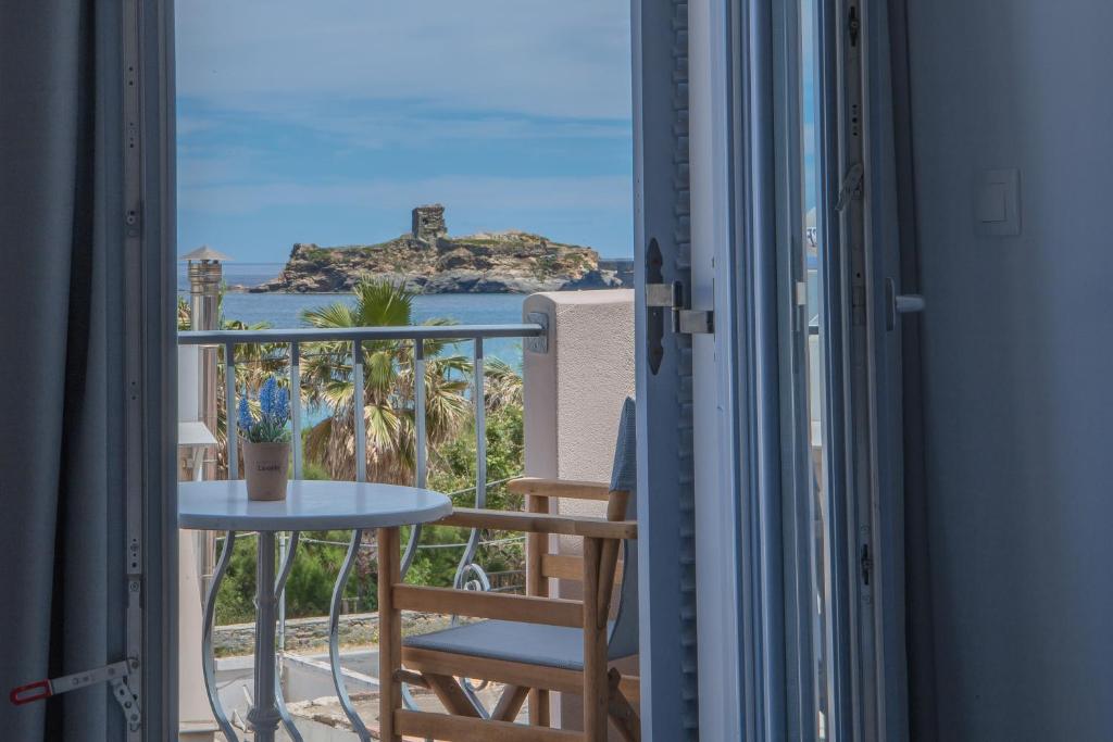 balcón con mesa y vistas al océano en Andros Blue, en Ándros