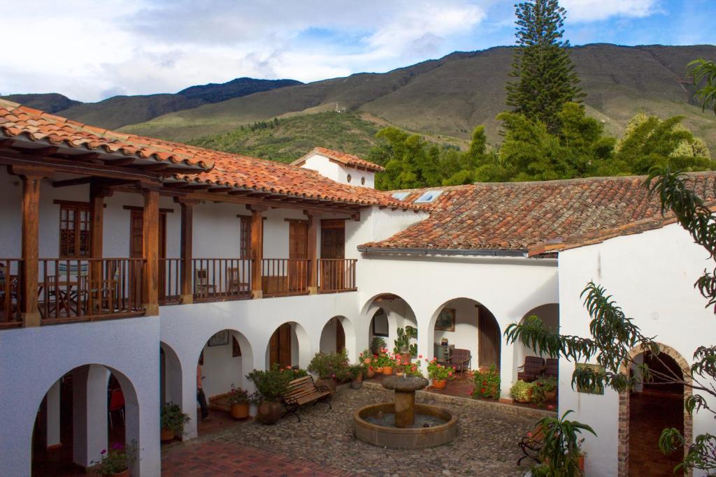 a building with a courtyard with a fountain and mountains at Posada Portal de la Villa in Villa de Leyva