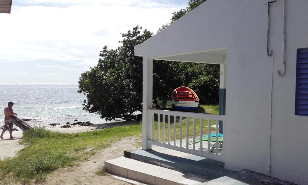 Un hombre caminando por la playa al lado de una casa en TI PARADIS DE l'ANSE FIGUIER VILLA voir site vacances en martinique, en Rivière-Pilote