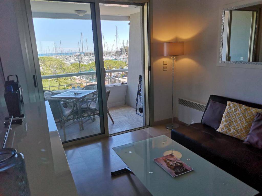 uma sala de estar com um sofá, uma mesa e uma varanda em Ducal, Marina Baie des Anges em Villeneuve-Loubet