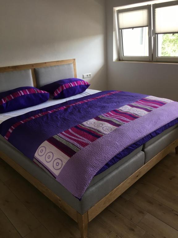 a bed with a purple blanket and pillows on it at Ferienwohnung Reh in Bad Rappenau