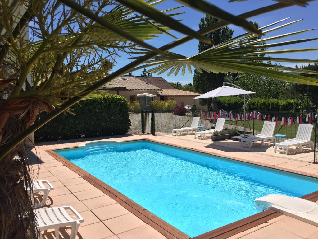 a swimming pool with chairs and an umbrella at Gîtes de La Condamine in Curbans