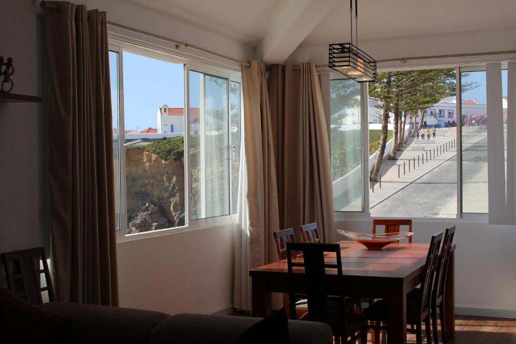 a dining room with a table and a large window at Apartamento Sto Estevão in Zambujeira do Mar