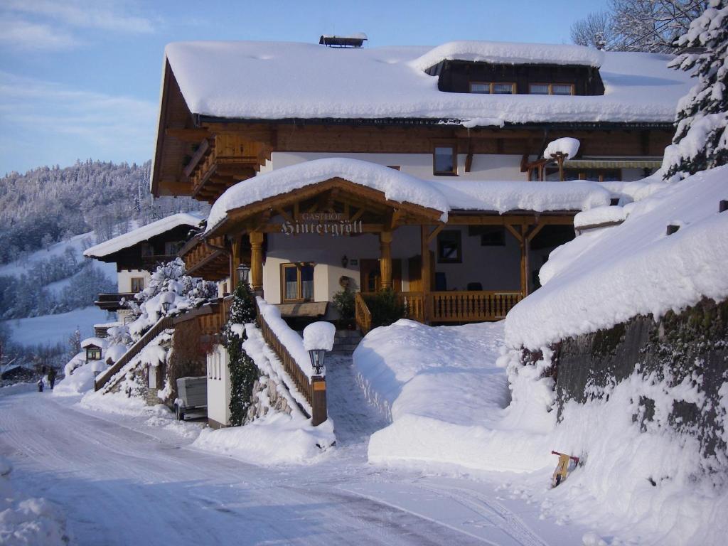 a house covered in snow in front of a road at Berggasthof Hintergföll in Unken