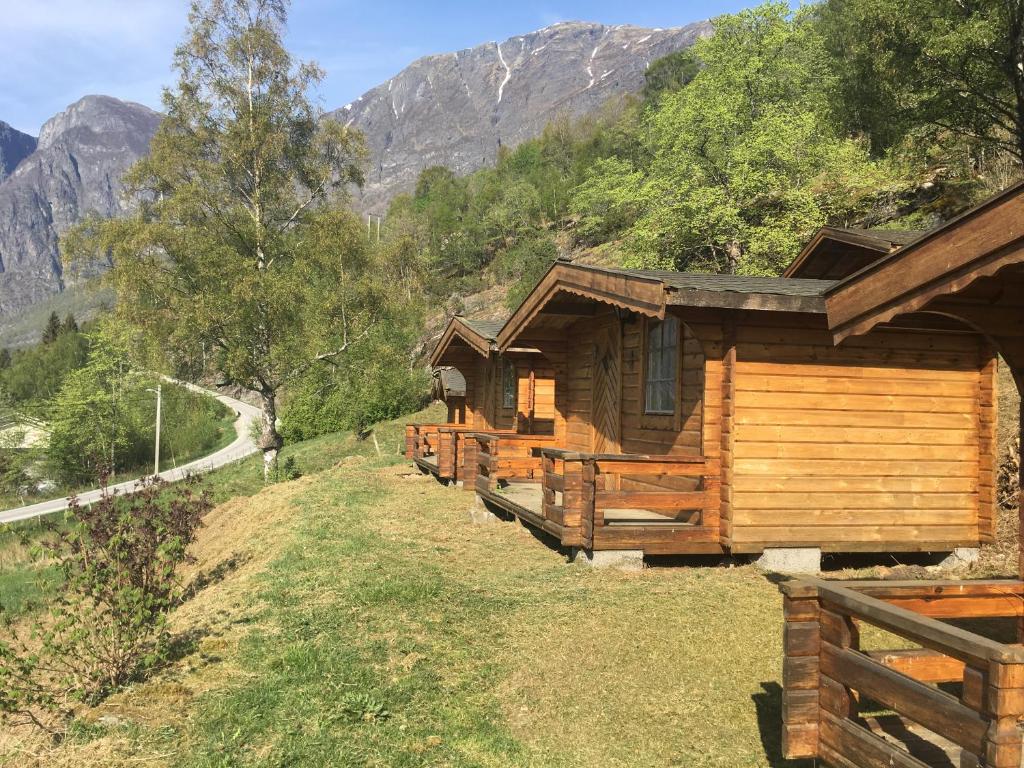 a row of wooden cabins on a hill with mountains at Winjum Cabin Aurland Stegastein in Aurland