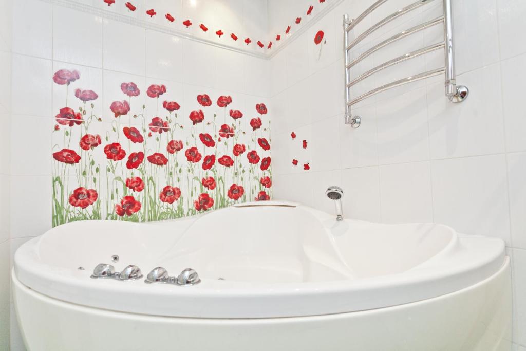 baño con lavabo blanco y flores rojas en la pared en KvartiraSvobodna - Apartments Kievskaya, en Moscú