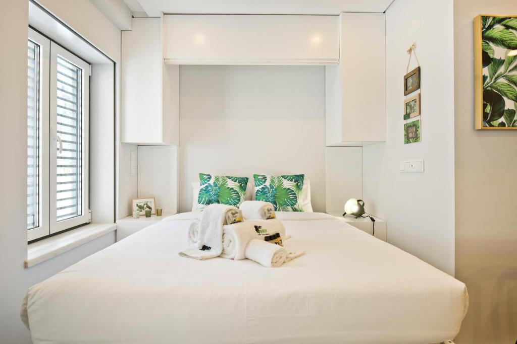 a bedroom with a large white bed with towels on it at BmyGuest Bruno’s 36 Apartments in Lisbon