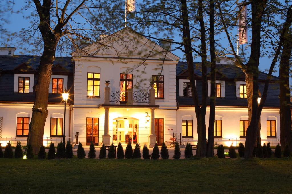 ein großes weißes Haus mit eingeschaltetem Licht in der Unterkunft Hotel Dwór Kościuszko in Krakau