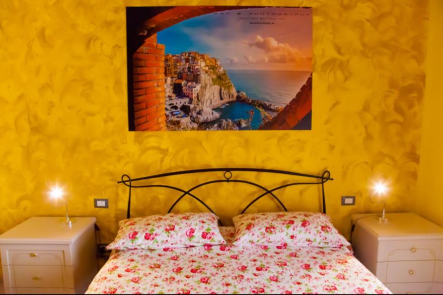 ラ・スペツィアにあるAffittacamere Rosyのベッドルーム1室(ベッド1台付)が備わります。壁には絵画が飾られています。