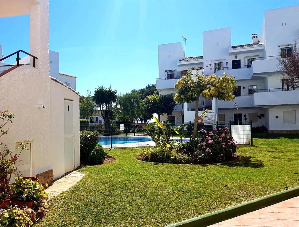 een groot appartementencomplex met een tuin met een zwembad bij Los Geranios - Beach Apartment in La Cala de Mijas