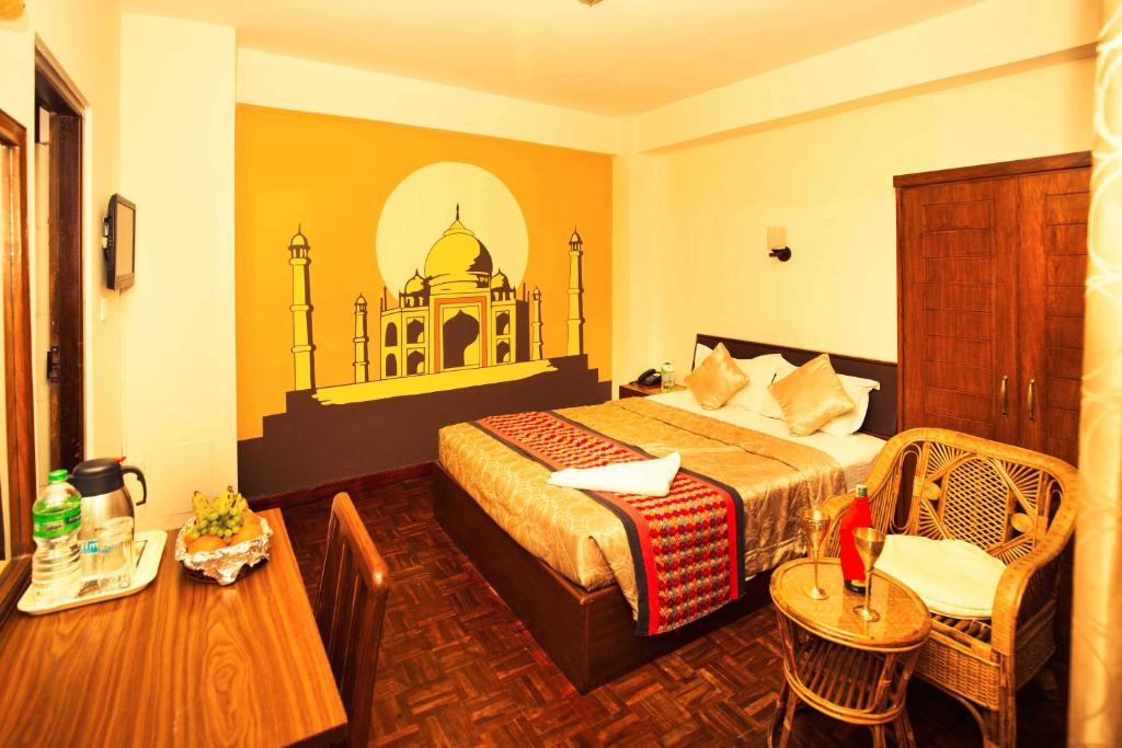 
a bedroom with a bed, chair, table and a lamp at Kathmandu Eco Hotel in Kathmandu
