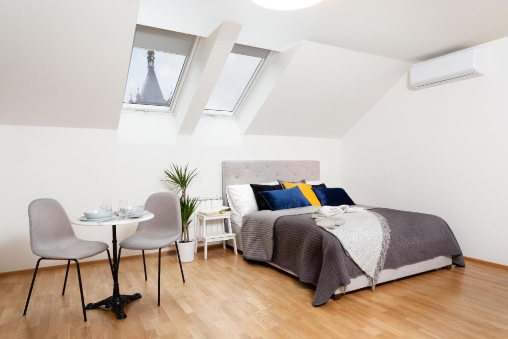 1 dormitorio con 1 cama, 1 mesa y 2 sillas en Cosy New Town Attic Studio, en Praga
