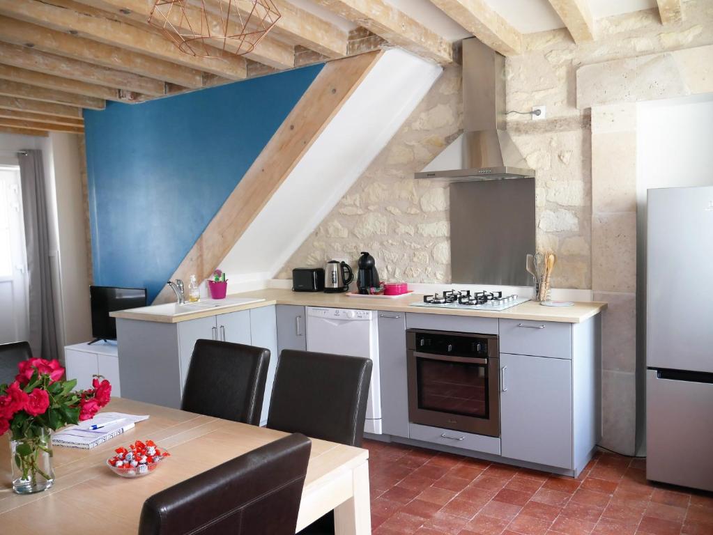 a kitchen with white cabinets and a table and a refrigerator at Casa Maya in Saint-Aignan