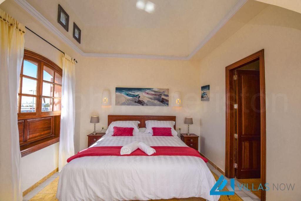 sypialnia z dużym łóżkiem z czerwonymi i białymi prześcieradłami w obiekcie Villa Valentina - LH156 By Villas Now Ltd w mieście Playa Blanca