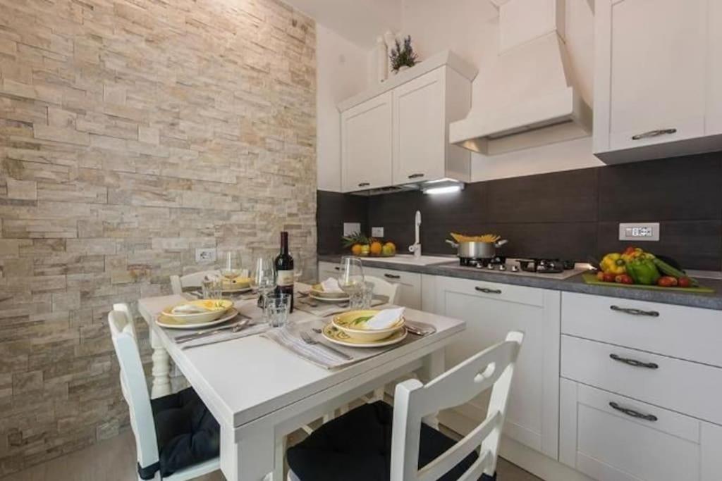 uma cozinha com uma mesa branca e armários brancos em Little box house em Florença