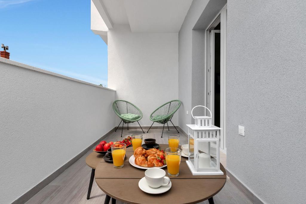 a table with a plate of food and orange juice at Apartments Morpheus in Makarska