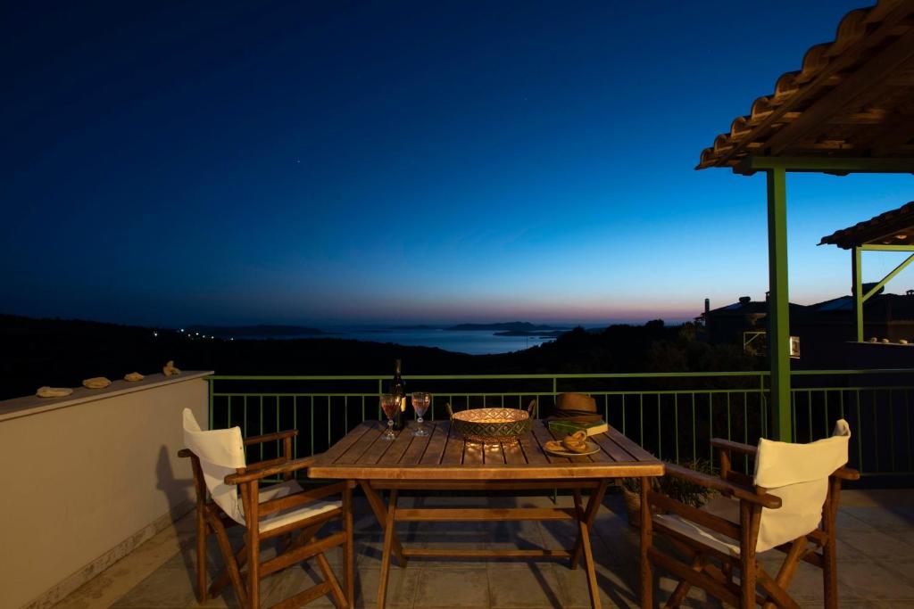 a table and chairs on a balcony at night at Chamaloni Cottages in Finikounta