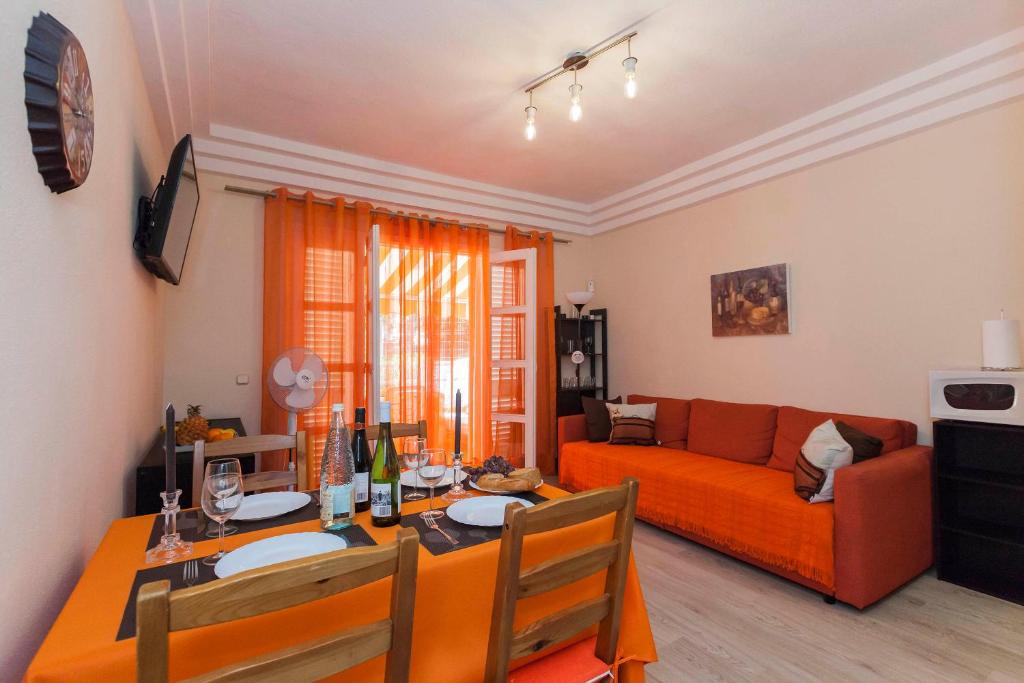 een woonkamer met een tafel en een oranje bank bij Cozy apartment Orlando in Adeje