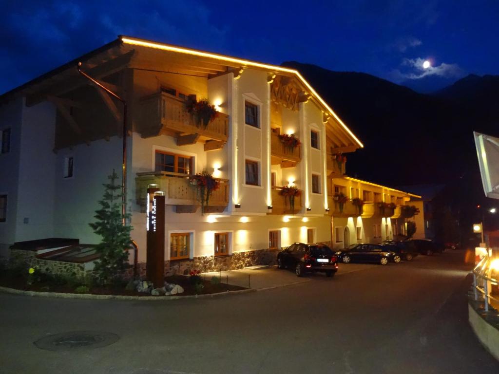 un grand bâtiment avec des voitures garées devant lui la nuit dans l'établissement Apart Hotel San Antonio, à Sankt Anton am Arlberg
