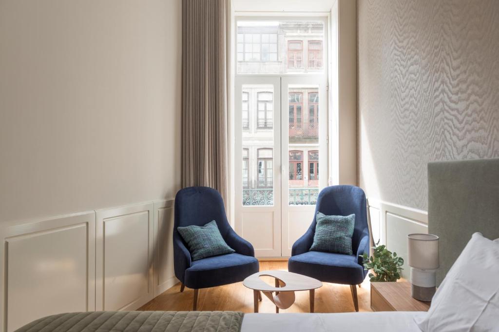 - deux chaises bleues et une table dans une chambre d'hôtel dans l'établissement Lit Apartments (2 Bedroom | City Center), à Porto