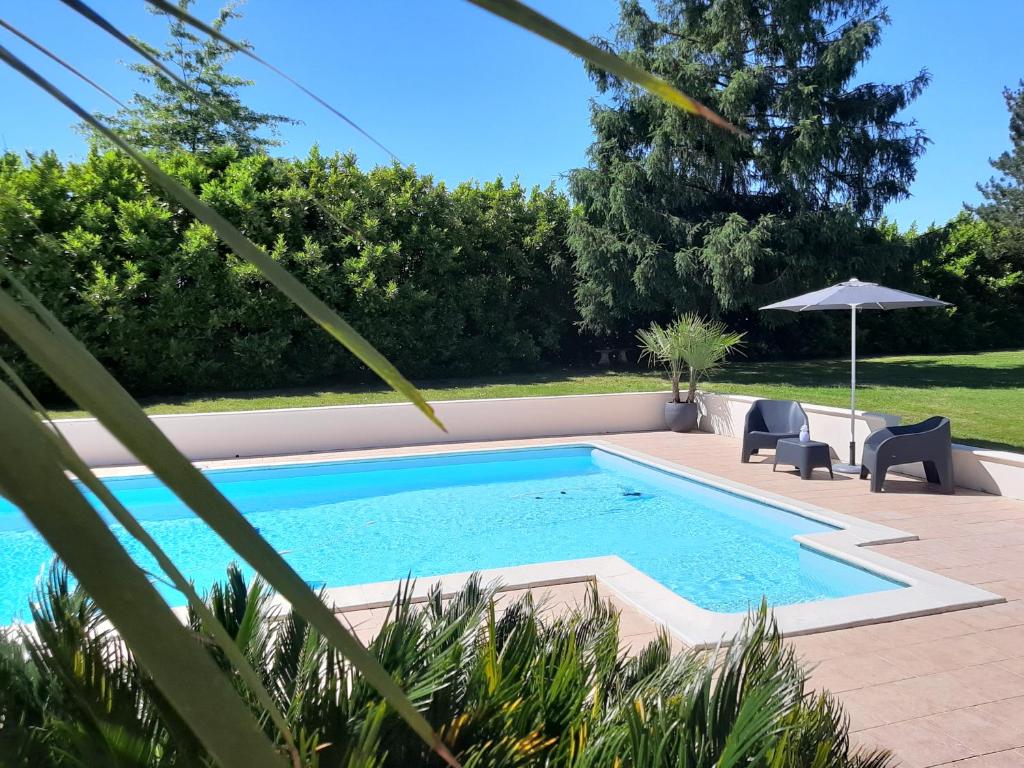 uma piscina com duas cadeiras e um guarda-sol em Gîte L'Ecureuil*** em MouscardÃ¨s