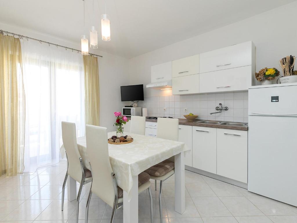 a white kitchen with a white table and chairs at Apartments Olea in Poreč