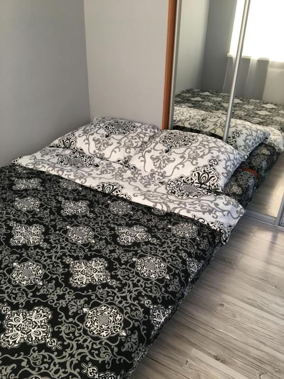 ein Bett mit einer schwarzen und weißen Bettdecke darauf in der Unterkunft Iwona in Świnoujście