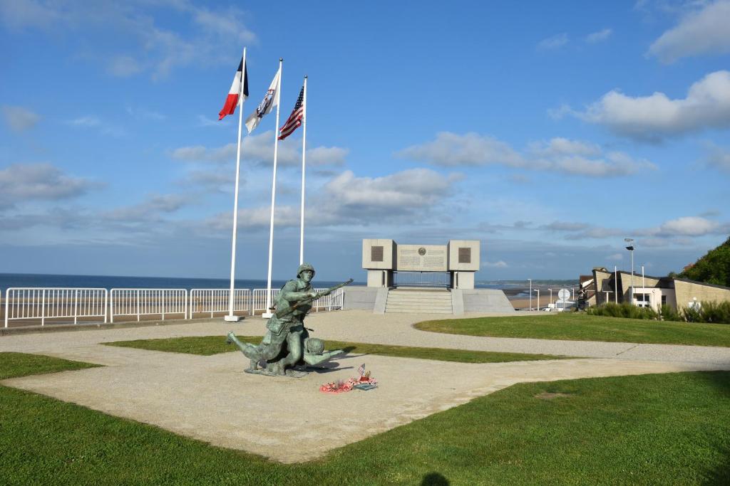 a statue next to the beach with three flags at Villa kahlo Omaha Beach in Colleville-sur-Mer