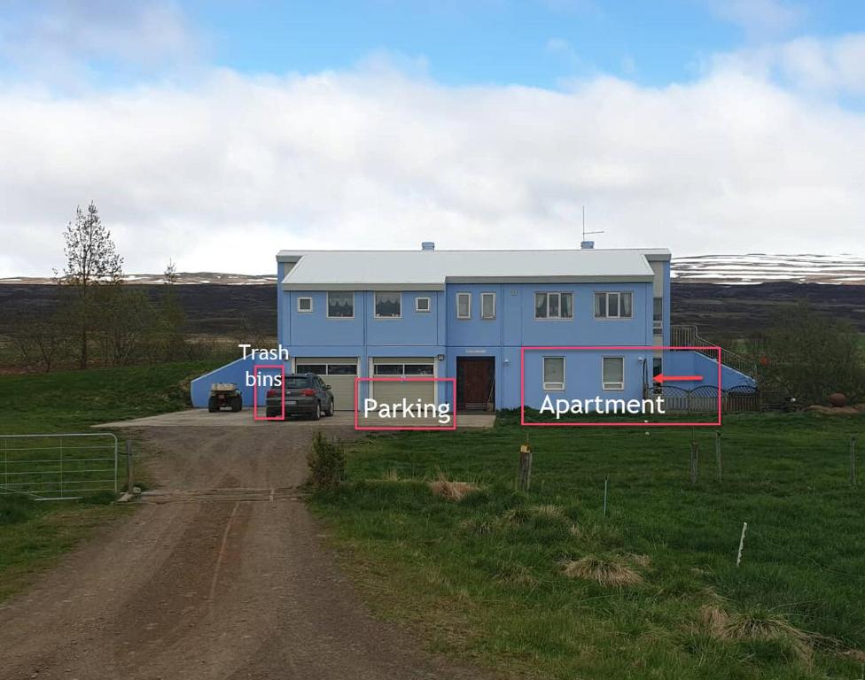 una casa azul al lado de un camino de tierra en Peaceful farm apartment, en Eiðar