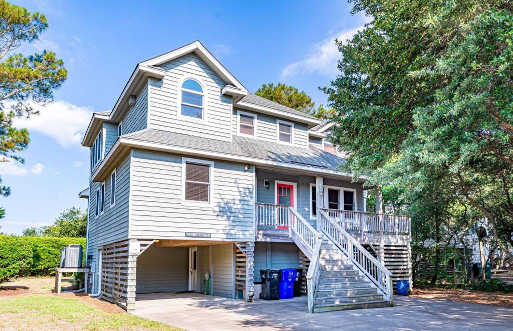 a white house with a staircase in front of it at Sunset Royale in Duck