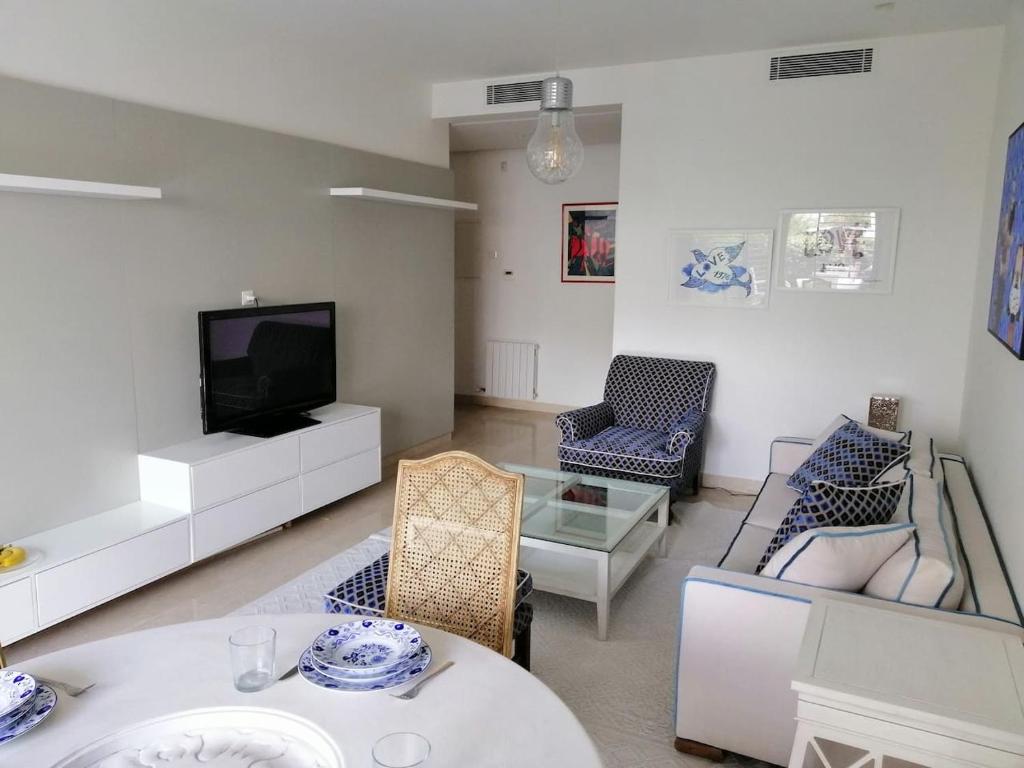 a living room with a tv and a table and chairs at luxueux pied-à-terre avec jardin et garage privés in Dār Şāliḩ Bey