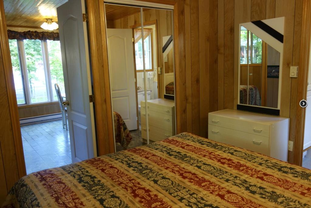 - une chambre avec un lit et un miroir dans l'établissement Camping Chalets Lac St-Augustin, à Québec