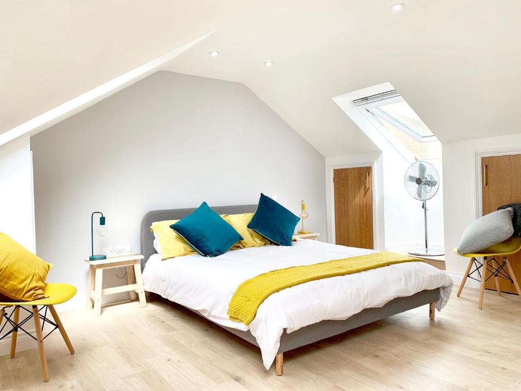 een slaapkamer met een bed met blauwe en gele kussens bij The Birches in Cambridge