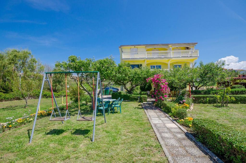 eine Schaukel in einem Garten mit einem Haus im Hintergrund in der Unterkunft Apartments Boza in Lopar