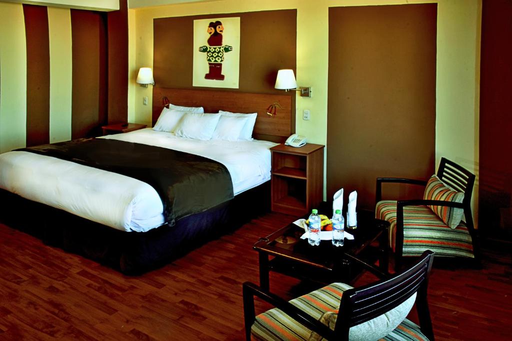 una camera d'albergo con letto, tavolo e sedie di Intiqa Hotel a Puno
