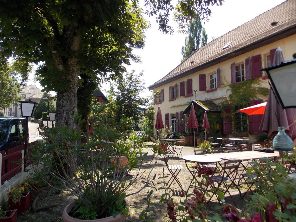 Ferrette的住宿－Chambres d'Hôtes Le Felseneck - NOUVEAU PROPRIÉTAIRE - NEW MANAGEMENT，一个带桌椅的庭院和一座建筑