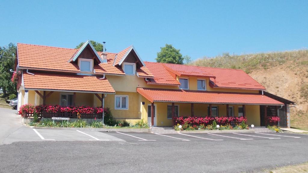 a building with orange roofs and flowers in a parking lot at Apartments Pavlić in Rakovica