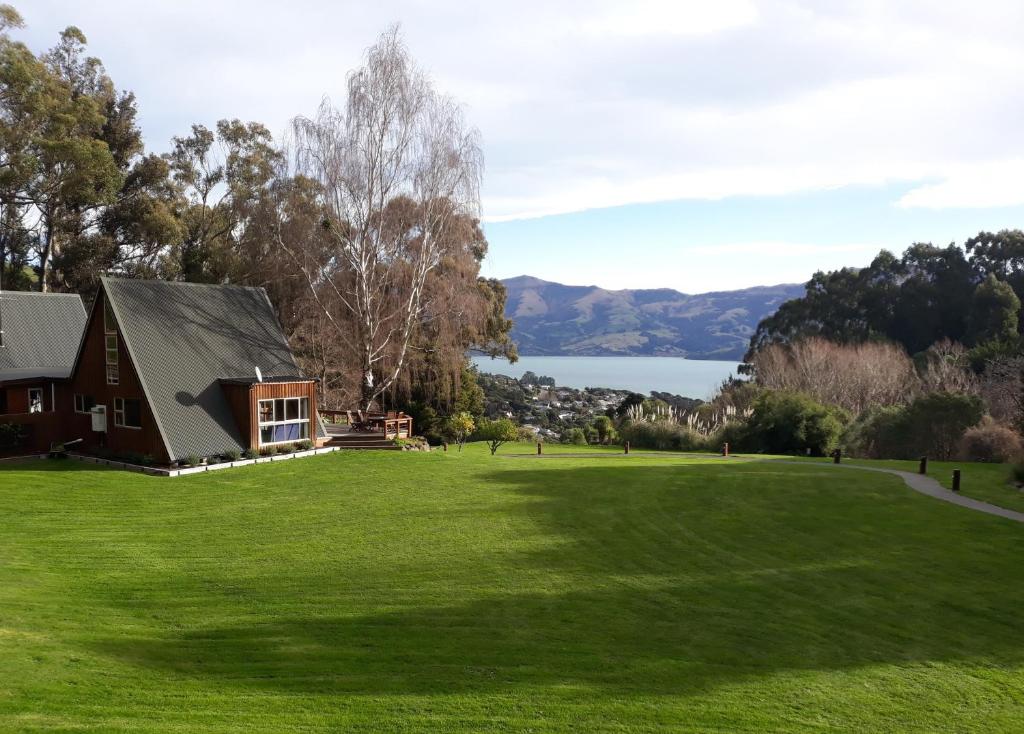 a house on a green field with a lake in the background at Mt Vernon in Akaroa