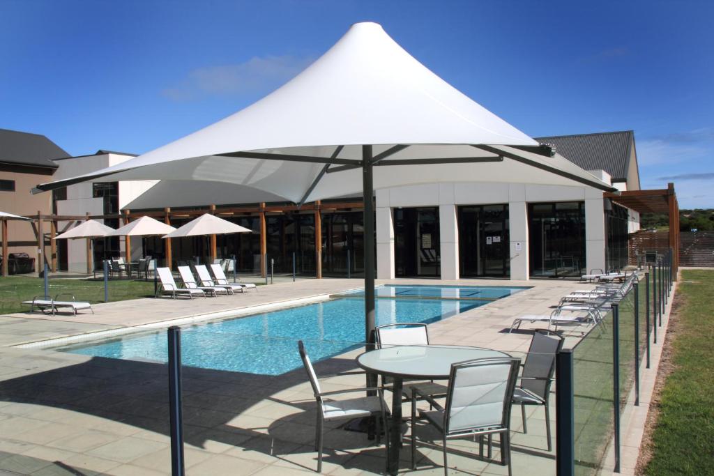 a table and chairs with an umbrella next to a pool at Barwon Heads Resort in Barwon Heads