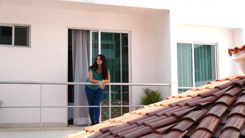 una mujer parada en el balcón de una casa en Metropolis Suites Ejecutivas en Puebla