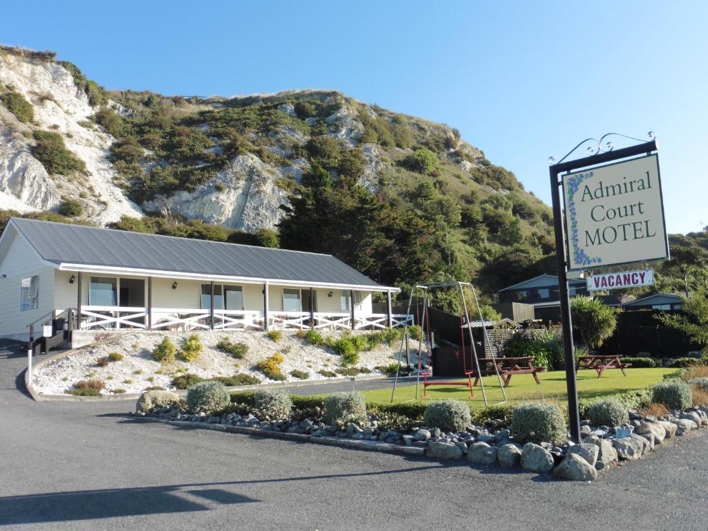 a sign for an animal court motel in front of a mountain at Admiral Court Motel Kaikoura in Kaikoura