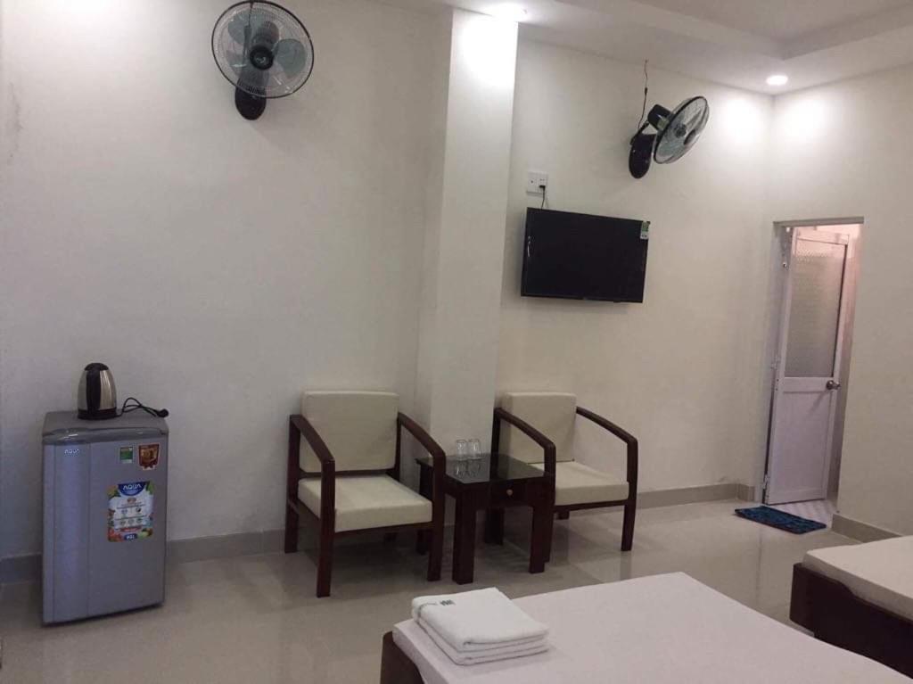 Zimmer mit 2 Stühlen, einem Tisch und einem Ventilator in der Unterkunft Trường Chính Sách Công Và Phát Triển Nông Thôn in Ho-Chi-Minh-Stadt