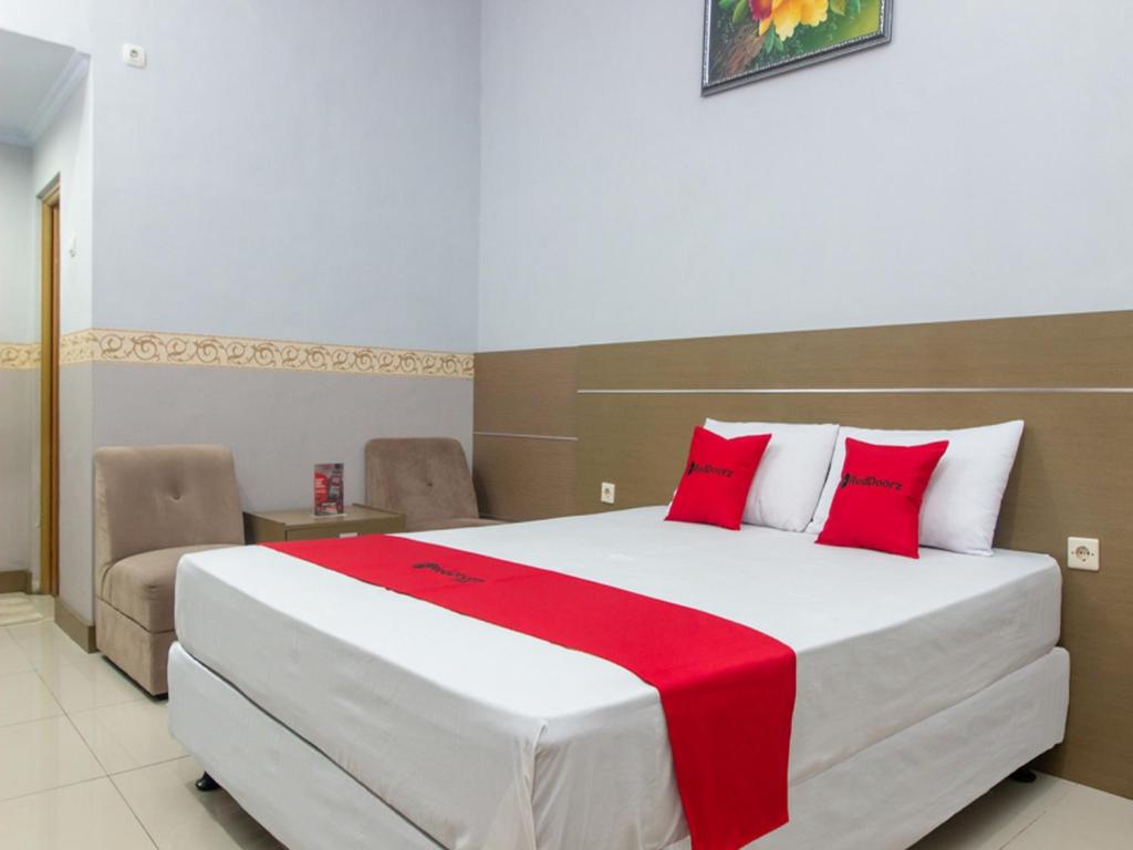 a bedroom with a large white bed with red pillows at RedDoorz near Goa Panggung in Pangandaran