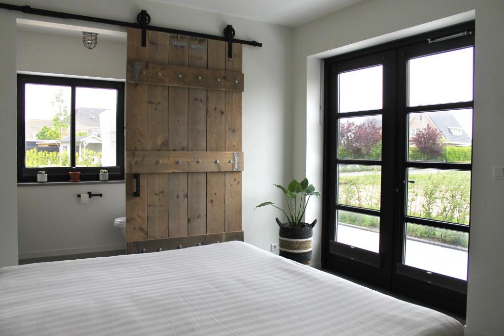 a bedroom with a large bed and two windows at Zeeuws Kot in Nieuwerkerk