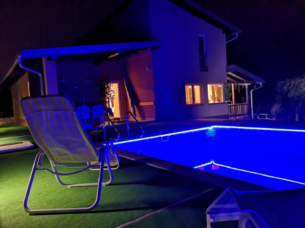 a chair sitting next to a swimming pool at night at Villa Meli in Visoko